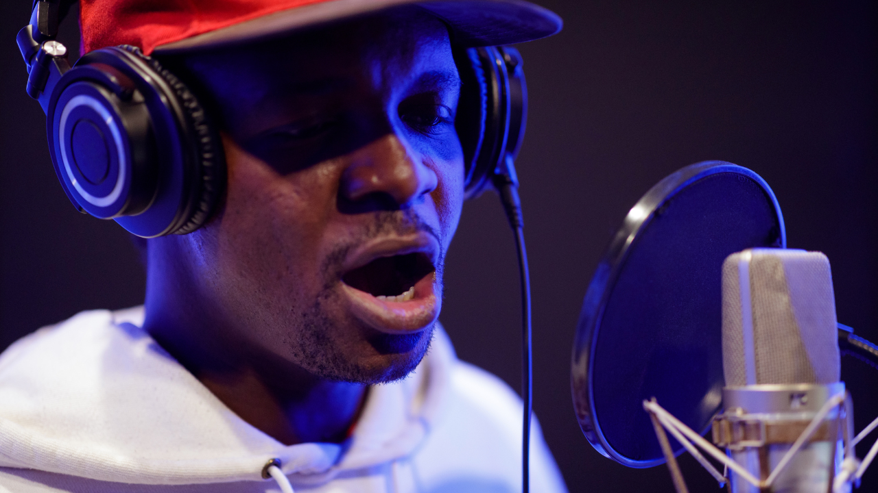 Rapper recording vocals in a home studio with a beatmaker producer